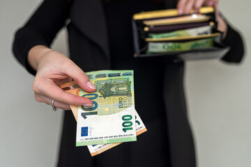 Beautiful young girl in black wants to pay euros from a wallet in a clothing store.