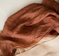 hand dyed clothes in warm natural tones on a bright background - text space -
slow fashion concept 