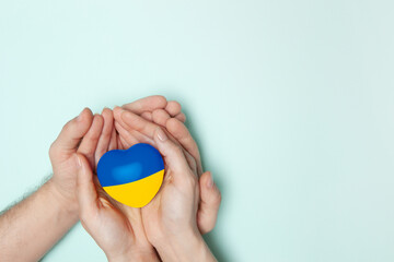 Heart with print the national flag of ukraine in female and male hands. Flat lay. Copy space.