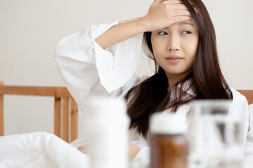 Fototapeta premium Asian woman feeling sick have a headache, coughing because of Coronavirus Covid-19. Protection and recovery from the illness quarantine at home, Stay at home.