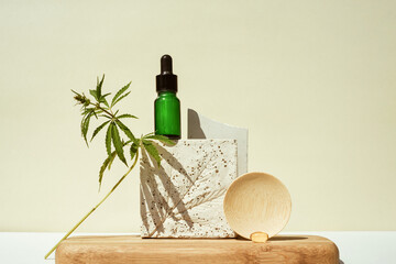 CBD oil in bottle and a cannabis bush, hemp in still life on geometric podium