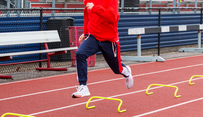 High school sprinter running over six inch mini hurdles on a track