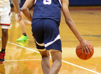 Rear view of basketball player dribbling the ball up court during a game