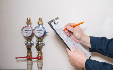 A man writes down the readings of water meters with a pen on paper. The concept of paying for...