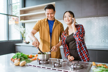 Young couple asking for some recipe while they cook at home together