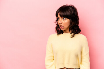 Young hispanic woman isolated on pink background being shocked because of something she has seen.