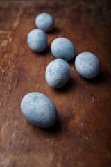 Fototapeta na wymiar Blue diy painted easter eggs on brown wooden rustic table background. Vertical shot