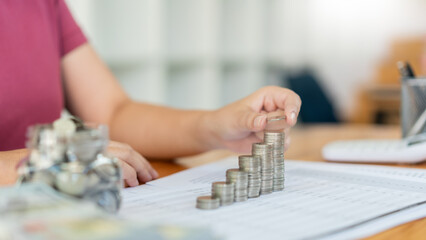 Saving concept the woman piling her coins to make the towers in different heights