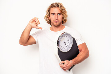 Young woman holding a scale isolated on white background showing a dislike gesture, thumbs down....