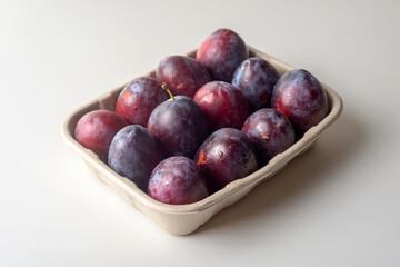 Organic sugar plums in ecological paper tray on light background.