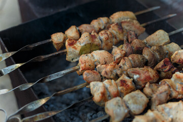 marinaded pork meat pieces on skewers frying over bonfire. Kebab or traditional shashlik cooking with lot of smoke.