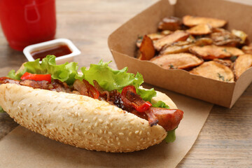 Hot dog, potato wedges and ketchup on wooden table, closeup. Fast food