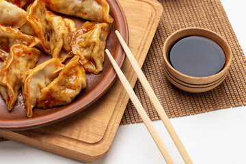 Gyoza dumplings and chopsticks on ceramic plate.