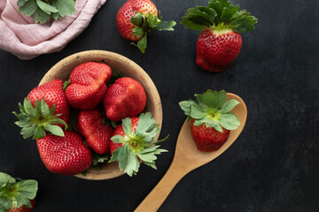 Bowl with delicious, red and juicy strawberries. Top view of a box with ripe strawberries on a dark background