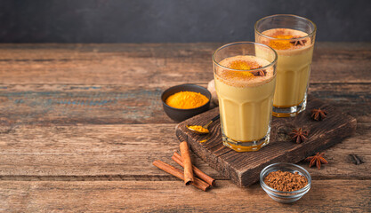 Turmeric latte with cinnamon and anise on a wooden background. Golden milk. Coffee with cinnamon, a healthy, revitalizing drink. Side view, copy space.