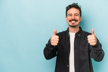 Young caucasian man isolated on blue background smiling and raising thumb up