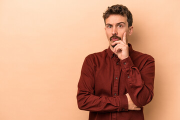Fototapeta premium Young caucasian man isolated on beige background looking sideways with doubtful and skeptical expression.