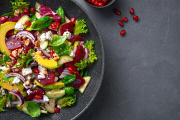 Salad with beetroot and avocado, fresh herbs, feta cheese, nuts and seeds on a gray-brown background. Top view, copy space.