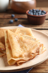 Delicious crepes served on wooden table, closeup
