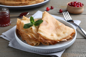 Delicious crepes served with mint on grey wooden table, closeup
