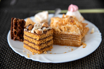 Leftovers in a plate on the table with sweets cakes, close-up