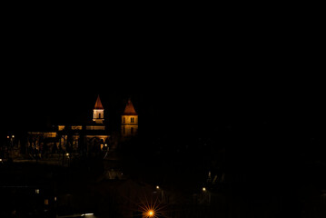 Kościół , pod wezwaniem św. Władysława , w Kunowie ( woj Świętokrzyskie ) ,  nocą , oświetlony , na tle świateł miasta .