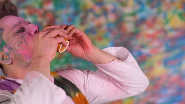 A young handsome man with a face covered with Holi colors drinking Thandai on Holi Festival 
. An Indian boy enjoying bhang and celebrating at home Holi party - the festival of colors  happy time ...