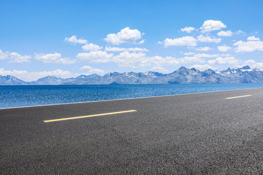 Asphalt road and lake with mountain natural scenery under blue sky