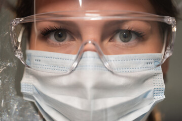 Young woman doctor or nurse working. Girl in medical mask, glasses and shield.