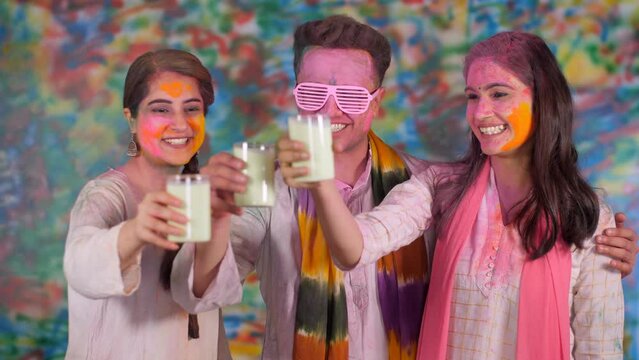 Young Indian friends drinking thandai and smiling - Happy faces  festive time  holi celebration. Excited friends celebrating the festival of colors and drinking bhang - Indian festival  college hol...