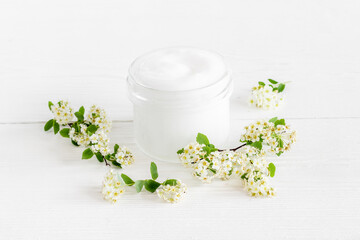 Fototapeta na wymiar White moisturizing cream cosmetic for spa treatment with blossoms flowers