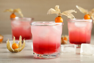 Refreshing cocktail decorated with physalis fruits on wooden table
