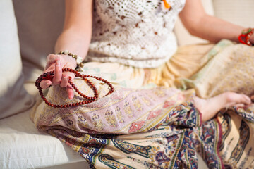 Woman at meditate place in lotus position using Mudra,  hand close up, strands of  beads used for...