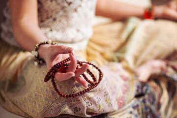 Woman at meditate place in lotus position using Mudra,  hand close up, strands of  beads used for...