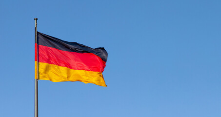 german flag in the wind with blue sky in background