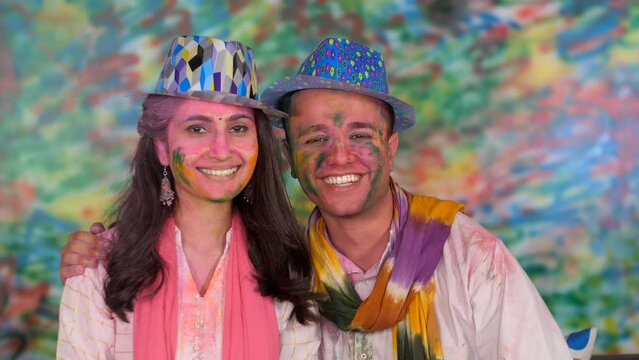 Cute Indian Couple wishing Happy Holi to friends and relatives on a video call - Beautiful  bonding. Smiling couple posing for the camera while celebrating the Indian festival of colors - Happy fac...