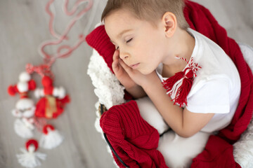 Cute child, blond boy, playing with white and red bracelet, martenitsa