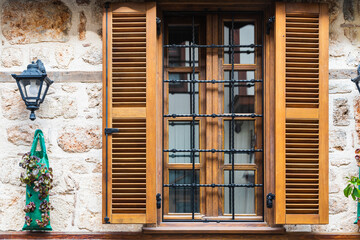 Close-up wall of a stone house with wooden windows and shutters. Old european architecture