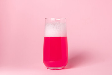 Pink drink in a glass on a pink background. Carbonated sweet water. delicious drink