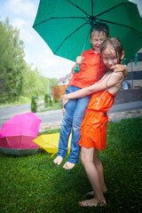Children having fun and joy with an umbrella on green grass. Boy and girl having rest together....