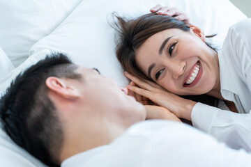 Portrait of Asian new marriage couple lying on bed and look each other.