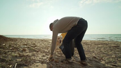 young handsome couple cleaning a beach from rubbish at sunrise 4k - Powered by Adobe