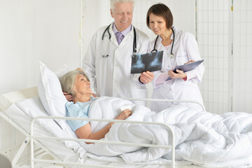 Portrait of senior woman in hospital with caring doctors