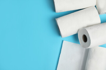 Rolls of paper towels on light blue background, space for text