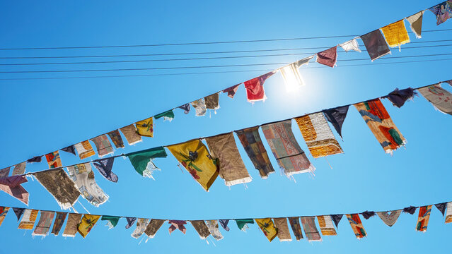 Karneval Hintergrund - Viele bunte Lumpen an Leine auf der Stra&szlig;e, als Schmuck f&uuml;r Fasching, mit blauem Himmel und Sonnenstrahlen