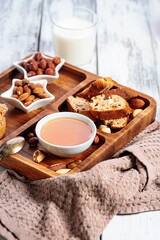 Homemade italian biscotti or cantuccini with almonds and dried fruits on white wooden background. Cookies and milk, honey and nuts. Traditional Italian cookies. Selective focus. Copy space