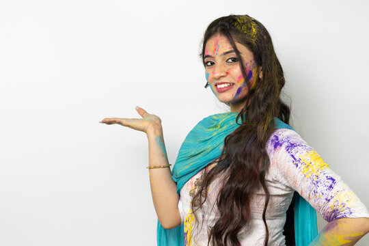 Young indian girl with powder colours on her face for festival of colours Holi, a popular hindu festival celebrated across india, isolated over white background, selective focus advertisement pose