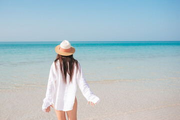 Fototapeta na wymiar Woman on the beach enjoying summer holidays looking at the sea