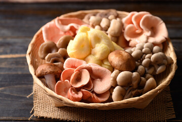 Mixed fresh mushroom (Edible mushroom) in bamboo basket on wooden background prepare for cooking