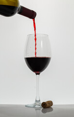 Crystal glass with red wine. Red wine being poured into wine glass on white background